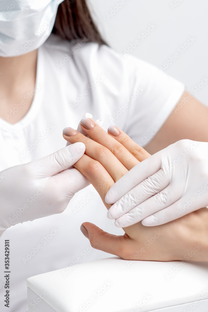 Manicurist holding woman's hand with beige polish on nails, close up. Manicurist holding woman's hand with beige polish on nails, close up.