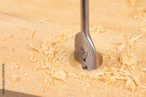 Fotografi closeup of a wood boring spade bit drilling a hole in a piece of wood