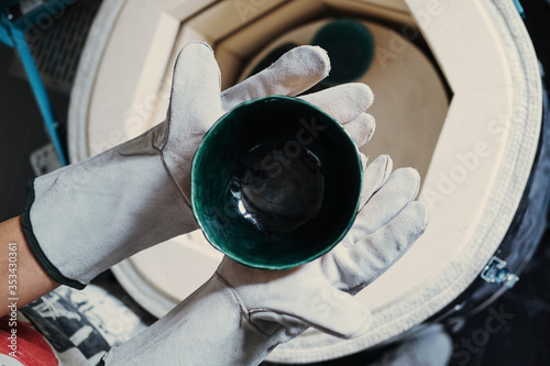 Clay master Hands wearing gloves holding cup from ceramic kiln photo