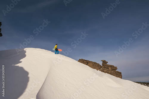 Snowboarder standing on a slope holding board. White snow background © Annatamila