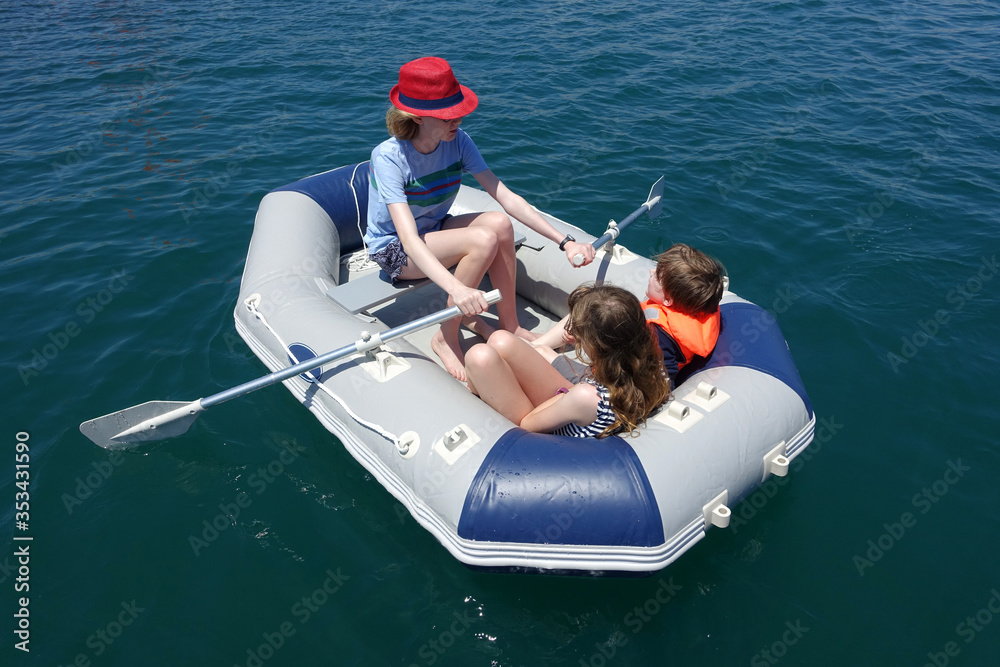 Naklejka premium Three children having fun in an inflatable dinghy