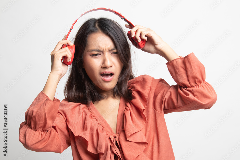 Too loud. portrait of young asian woman holding headphones and making unhappy face . Too loud. portrait of young asian woman holding headphones and making unhappy face .