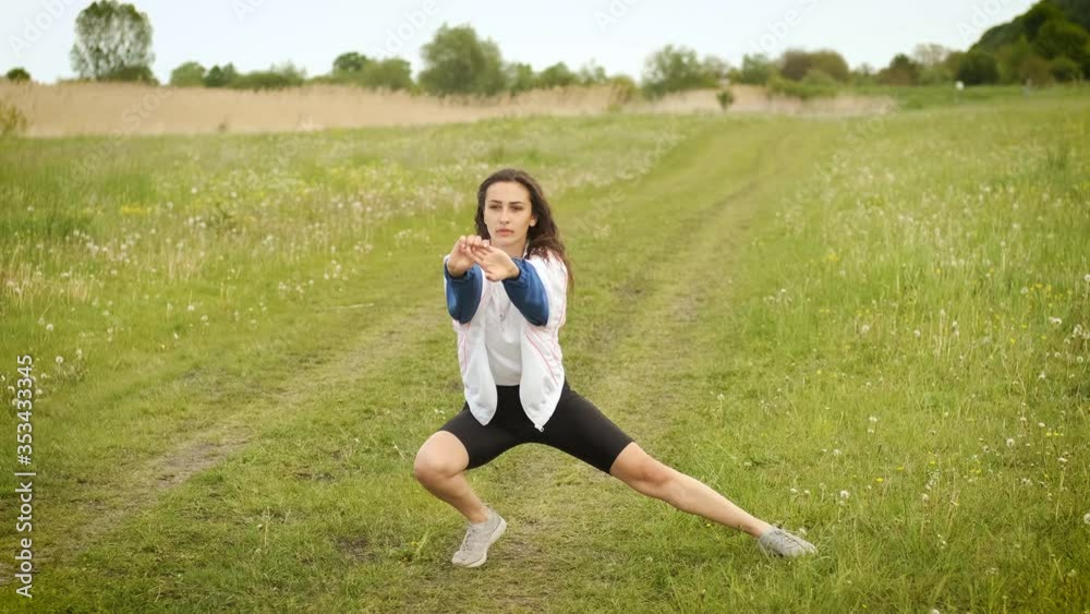25 year old girl of sporty appearance is doing a warm-up in the park near the lake 25 year old girl of sporty appearance is doing a warm-up in the park near the lake