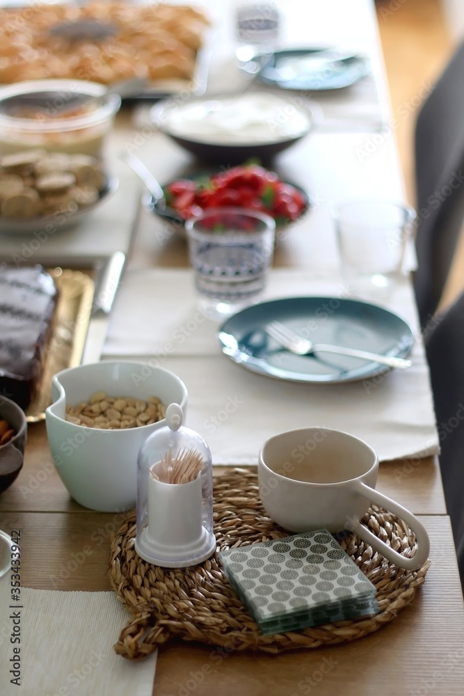 Table setting with colorful dishes and various food: crackers, hummus, homemade bread, cake, strawberries and whipped cream. Selective focus. Table setting with colorful dishes and various food: crackers, hummus, homemade bread, cake, strawberries and whipped cream. Selective focus.