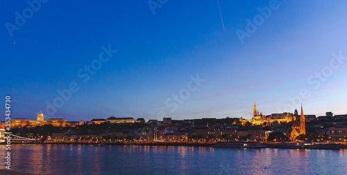 Cityscape of Budapest and Danube river in sunset time. Blue sky and yellow lights of urban city with famous landmarks. Tourism concept of old capital in Hungary.