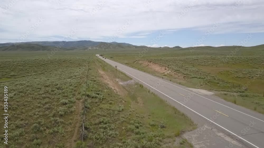 Aerial shot of vehicles moving on country road against cloudy sky, drone flying forward over green landscape - Boise, Idaho Aerial shot of vehicles moving on country road against cloudy sky, drone flying forward over green landscape - Boise, Idaho