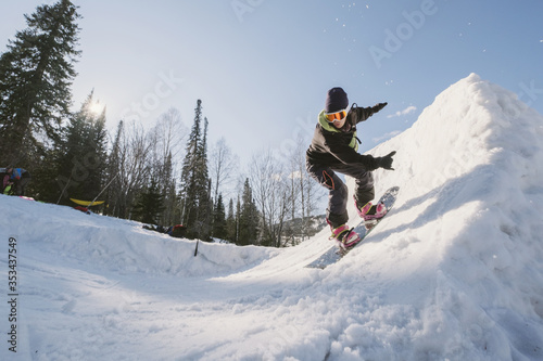 Snowboarder woman jumping on quarter pipe snowboard in winter sunny day. Freestyle snowboard training