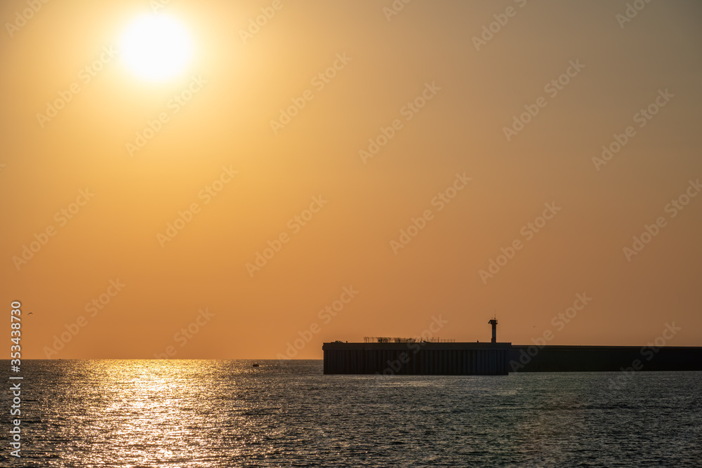 Beautiful yellow and orange sunset over the sea. The sun goes down over the sea. Silhouette of a pier at sunset