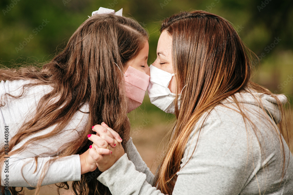 Portrait of young mother with young daughter using mask. Mother and daughter wearing mask to protect Covid-19, quarantine. Kiss. Stay at home concept.