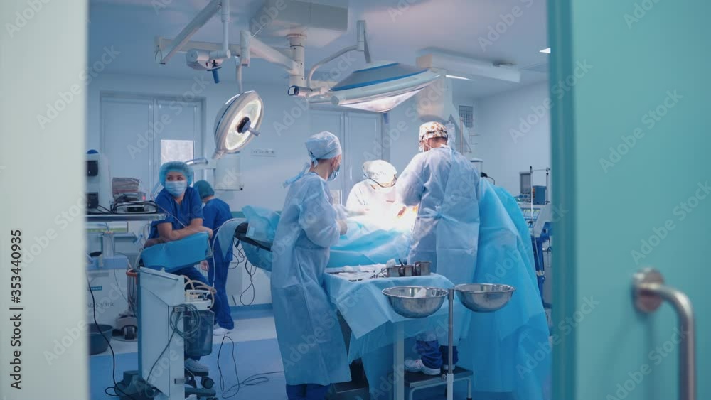 Operation room with specialists. Teamwork of surgeons performing operation on the background of modern equipment in private clinic. Operation room with specialists. Teamwork of surgeons performing operation on the background of modern equipment in private clinic.