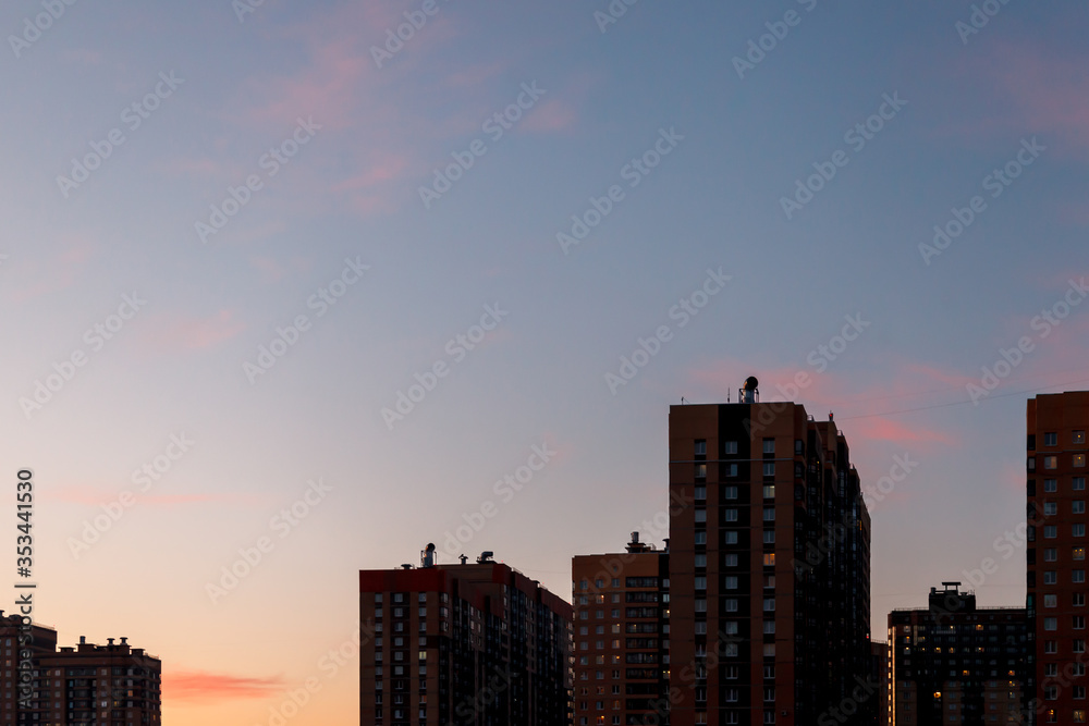 Tops of skyscrapers against clear blue sky. Skyscrapers against background of evening sunset sky with clouds. View of buildings with space for your creativity, place an inscription or logo