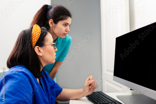 Two nurses using a computer in a x-ray room