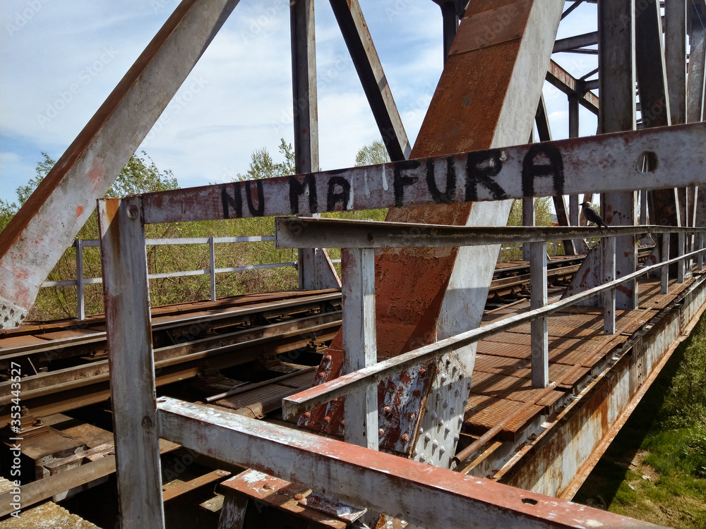 A rusted railroad bridge on a sunny day with cloudy blue sky on the background. A rusted railroad bridge on a sunny day with cloudy blue sky on the background.