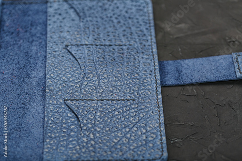 Blue leather wallet on a black textured background. © Alexander