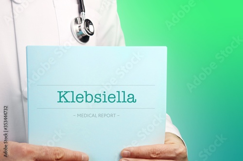 Klebsiella. Doctor holds documents in his hands. Text is on the paper/medical report. Green background. photo
