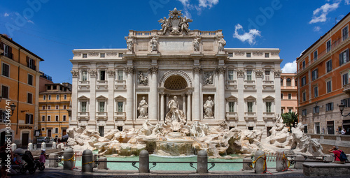 The baroque masterpiece of the Trevi Fountain in Rome, one of the most popular tourist attractions in the city, on a summer afternoon against a blue sky.