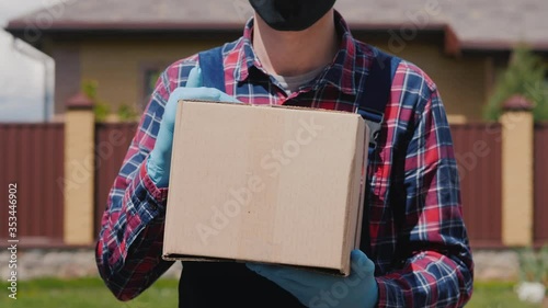 The messenger in the gloves holds a box with a parcel. Delivery of orders to the buyer's door photo