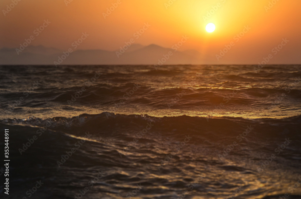 sunset over the sea, cloudless, the whole scene is colored in gold and orange