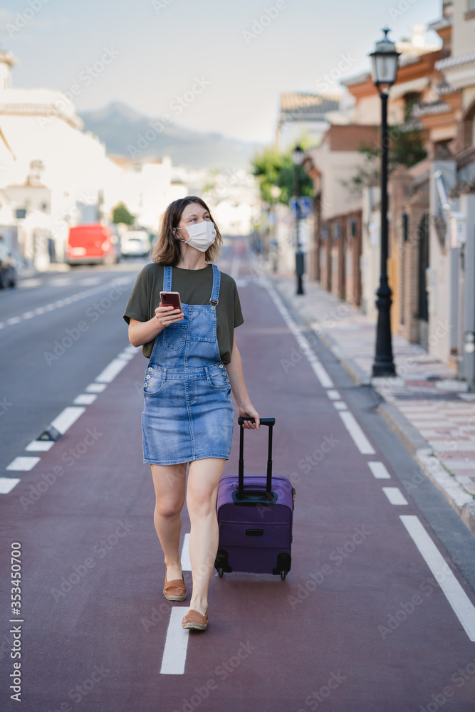 traveller with protection mask against coronavirus visiting the city with her suitcase traveller with protection mask against coronavirus visiting the city with her suitcase