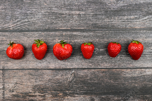 Fototapeta Naklejka Na Ścianę i Meble -  red strawberries lined up against a dark wooden background