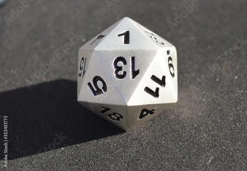 d20 twenty-sided silver metallic die dice on foam background in bright sunshine - 1 on top face photo