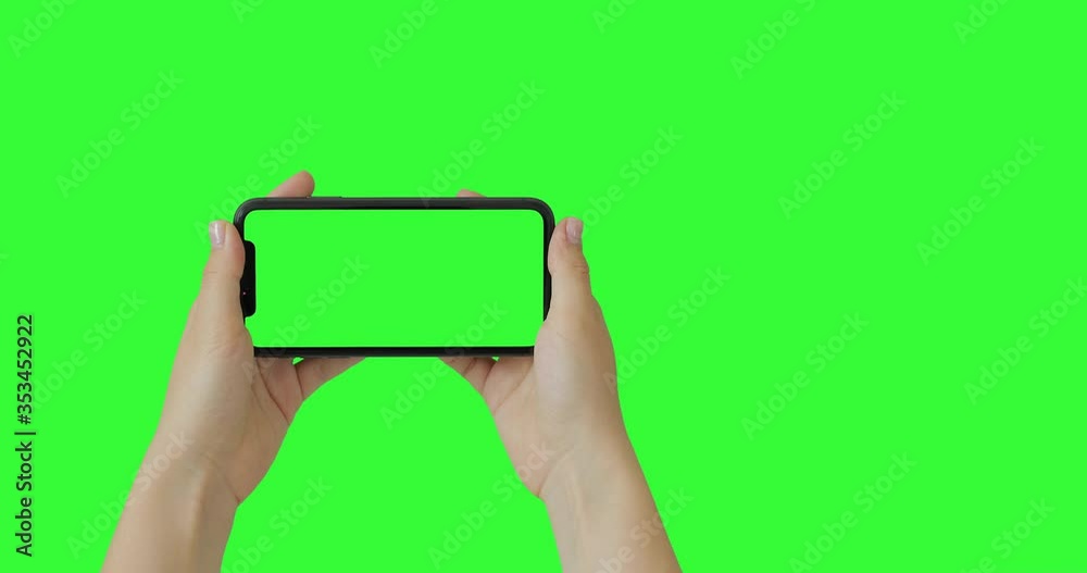 Female woman hands holding the smartphone on green screen chroma key background. Mobile phone mock-up for your product. The iPhone 11 model in horizontal orientation landscape mode. Female woman hands holding the smartphone on green screen chroma key background. Mobile phone mock-up for your product. The iPhone 11 model in horizontal orientation landscape mode.