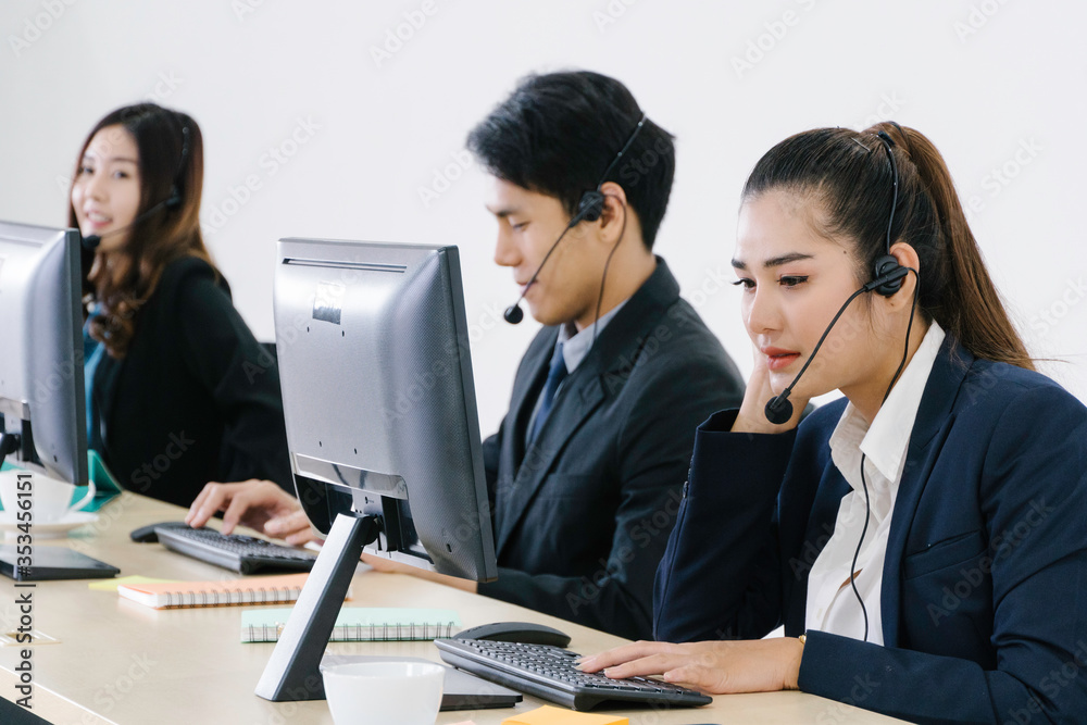 Young Asian business call center man and woman with headset sitting in office desk using computer. work for telemarketing. consulting service or customer support. operator agent giving advice on phone Young Asian business call center man and woman with headset sitting in office desk using computer. work for telemarketing. consulting service or customer support. operator agent giving advice on phone