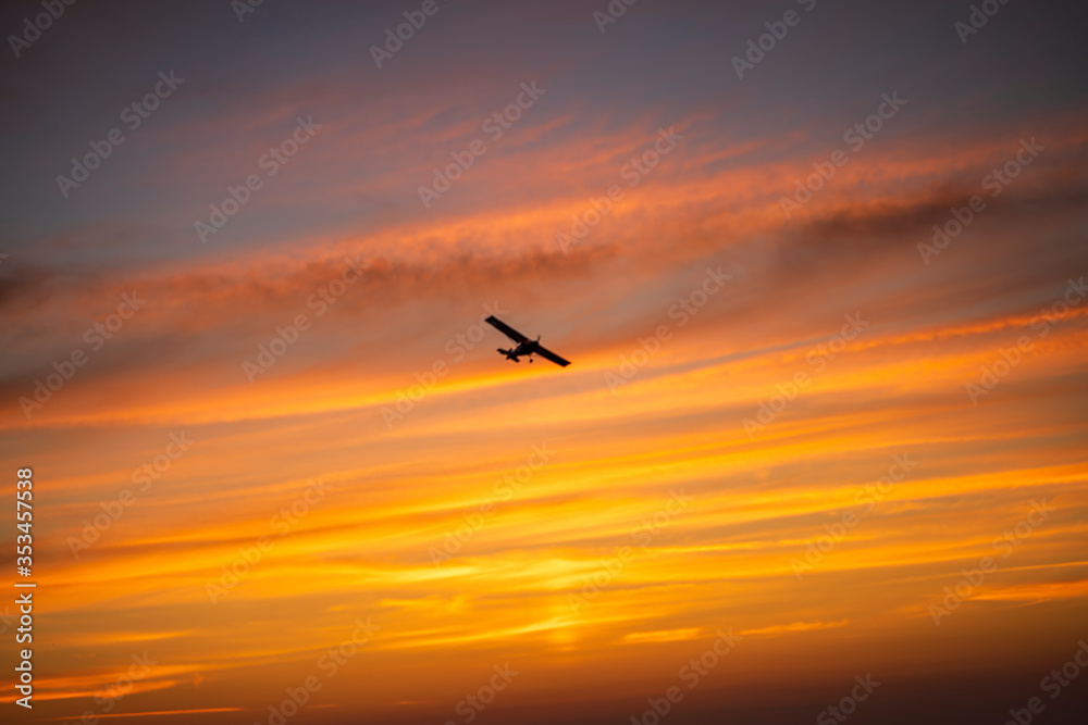 The plane flies across the sunset sky in the evening, bright orange colors, stripes.