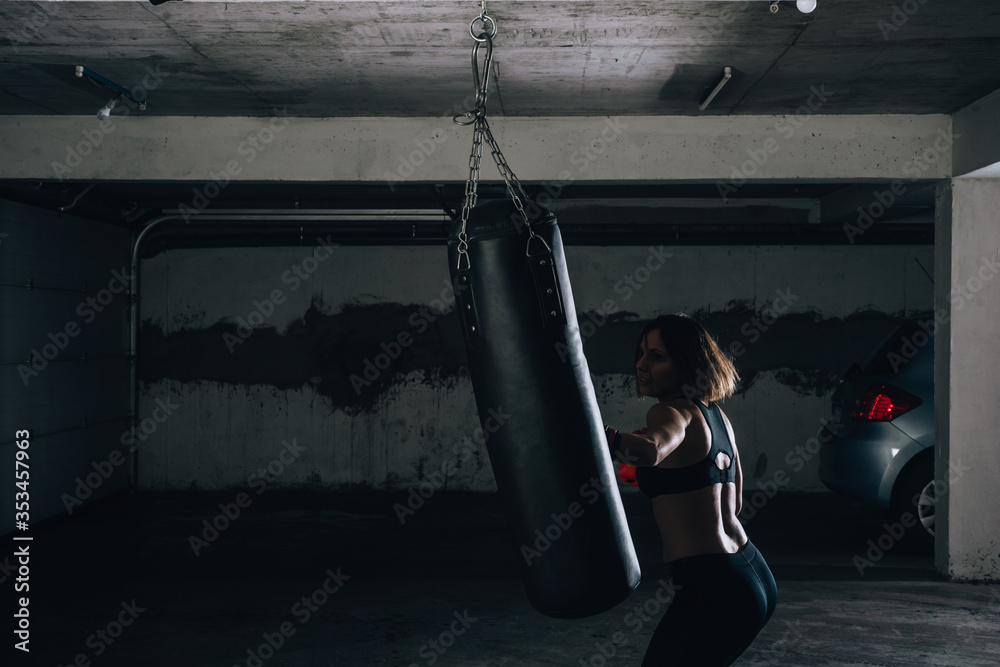 Silhouette picture of beautiful brunette punching the boxing bag