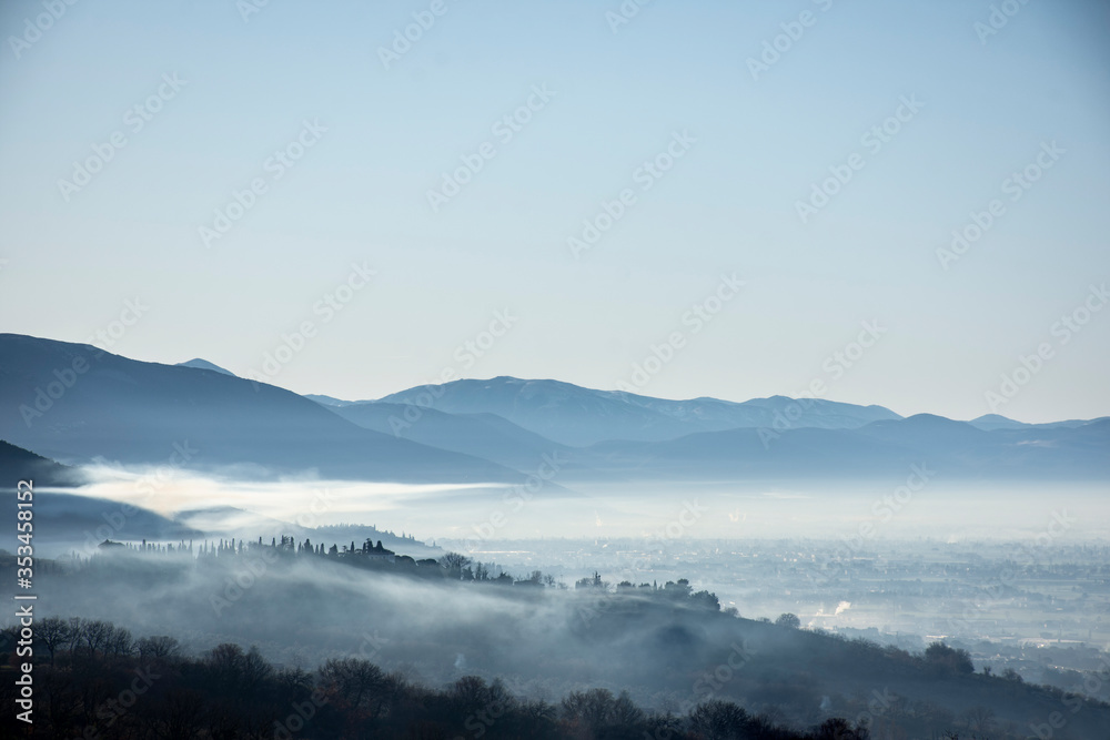 Fototapeta premium Pueblo ubicado en las colinas durante amanecer de día con niebla