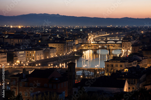 Fototapeta Naklejka Na Ścianę i Meble -  Vista de ciudad de Florencia atravesada por río al anochecer con colinas de fondo
