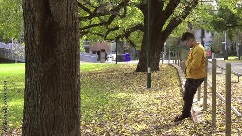 Alone men with yellow jacket using smartphone in the park of the fall.