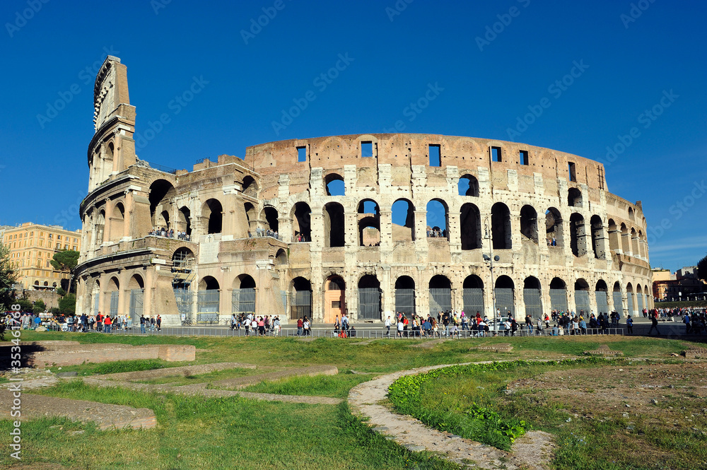 View of the exterior of the Colosseum, Coliseum,  in Rome with green meadow in front on a spring day