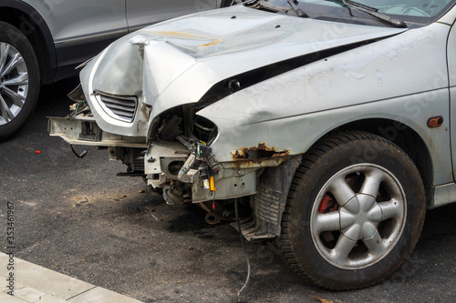 Front part of a grey passenger car damaged in an accident or traffic accident. Broken-down car, insurance payments. Disposal of damaged cars. Repair of machines.