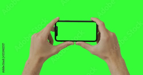 Male man hands holding the smartphone on green screen chroma key background. Mobile phone mock-up for your product. The iPhone 11 model in horizontal orientation landscape mode. USA, NY