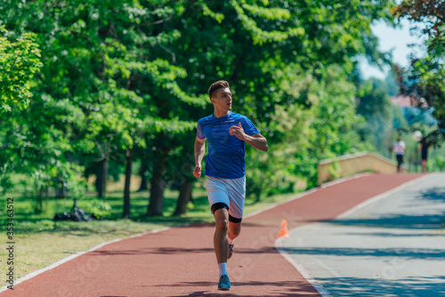 Handsome man jogging during sunny morning out on the race track © qunica.com