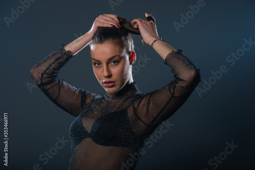 Fashion portrait of an attractive brunette girl holding and pulling her ponytail.