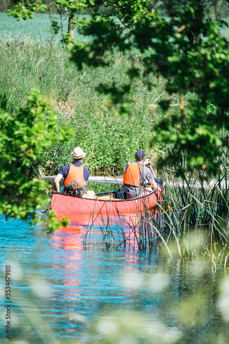 The river Stour in Suffolk is one of the more picturesque rivers to canoe. Two man canoeing rear view though Stour river, Nayland, Suffolk, England