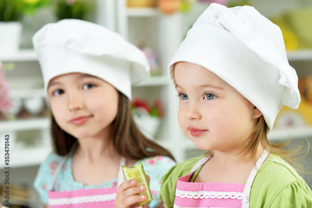 Portrait of cute girls with cucumber together in kitchen at home Portrait of cute girls with cucumber together in kitchen at home