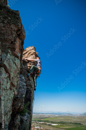 Male rock climber climbing along a roof in a cliff