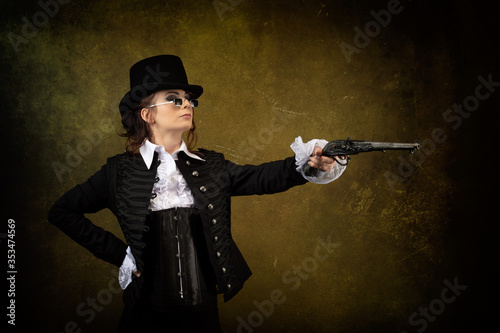 Portrait of a young Victorian woman wearing a top hat, black glasses, holding a musket gun