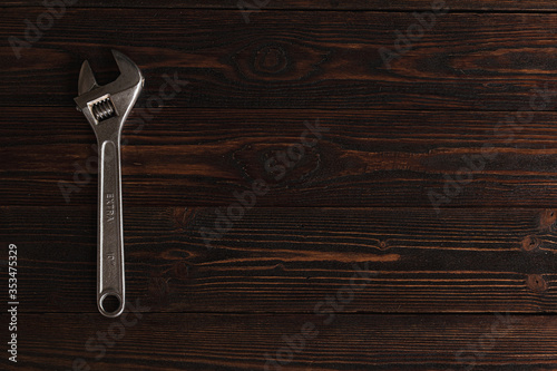 .Steel wrench on a wooden brown background. Metal wrench top view.