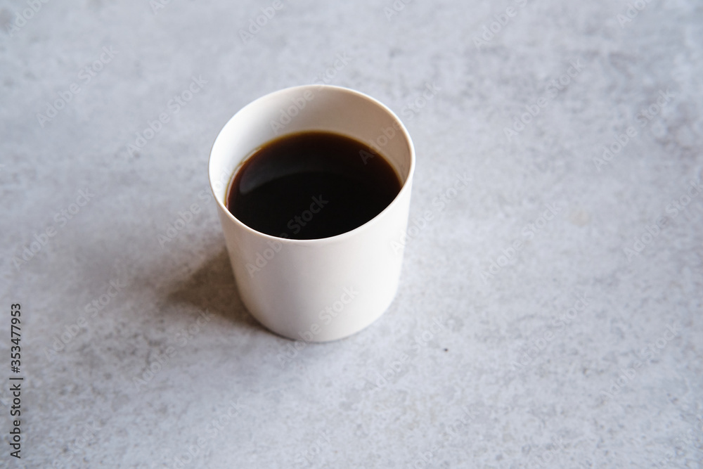 Cup of black coffee in a handmade white ceramics mug, white marble background