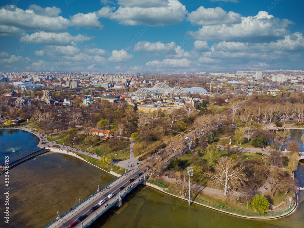 Top view on Secheni baths, Budapest city park. People are resting on the green grass. Lakes and bridge in the park. Spring. Trees without leaves and with green leaves. Top view on Secheni baths, Budapest city park. People are resting on the green grass. Lakes and bridge in the park. Spring. Trees without leaves and with green leaves.