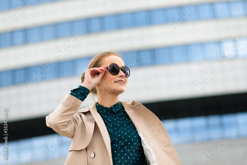 Beautiful young serious caucasian businesswoman in glasses while walking at break in the city.