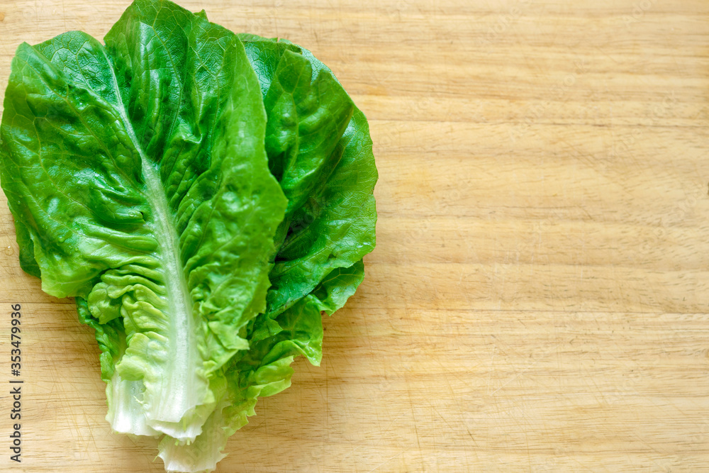 Romano lettuce closeup on blurred wooden board Romano lettuce closeup on blurred wooden board