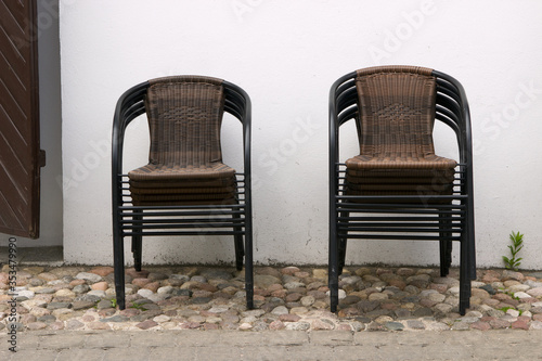 There are no visitors in the street cafe, the restaurant is closed. Wicker chairs stacked on top of one another.