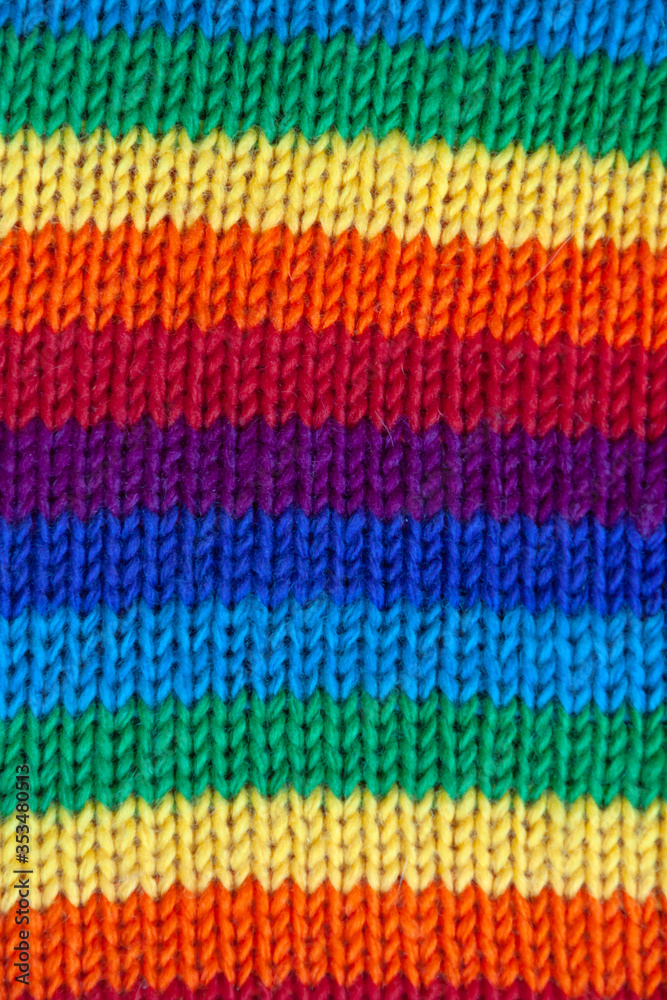 A knitted wool fabric in the colors of the rainbow. Fun background. Horizontal stripe.
