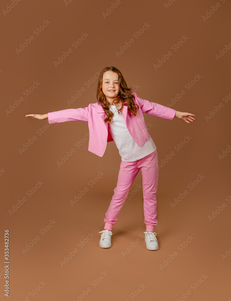© Julie Boro - cute girl in a pink tracksuit does gymnastics and does exercises on a beige background