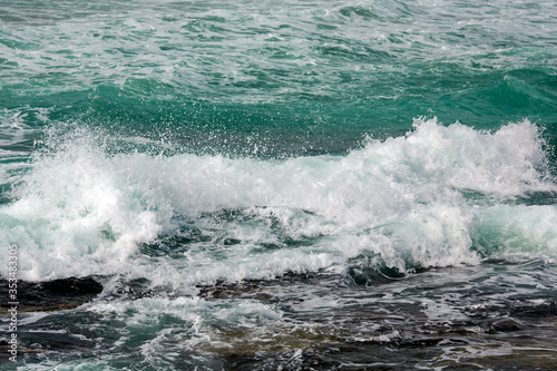 Small waves of the turquoise Mediterranean Sea on a rocky shore